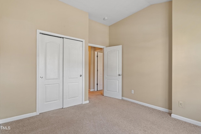 unfurnished bedroom featuring a closet, carpet flooring, baseboards, and vaulted ceiling