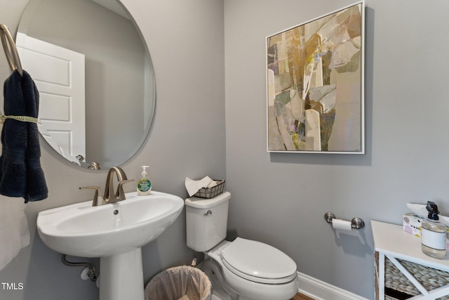 bathroom with a sink, toilet, and baseboards