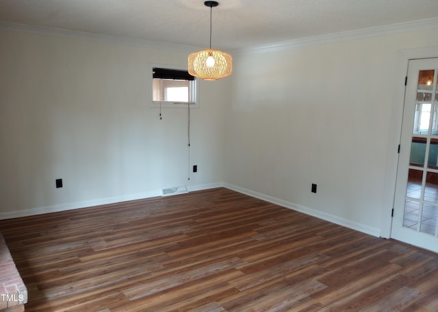 unfurnished dining area featuring baseboards, visible vents, ornamental molding, and wood finished floors