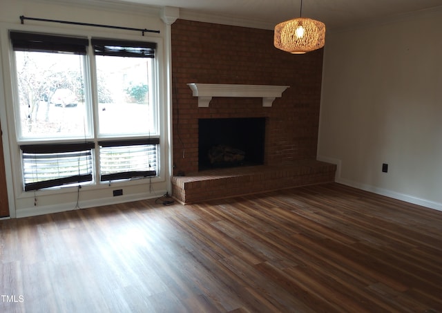 unfurnished living room with ornamental molding, a brick fireplace, baseboards, and wood finished floors