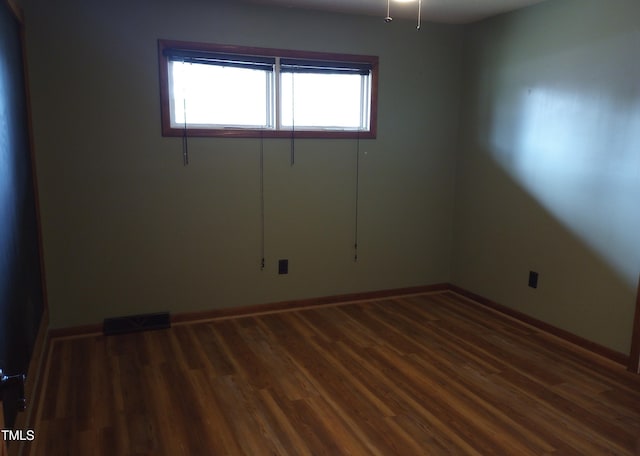 spare room featuring baseboards, visible vents, and wood finished floors