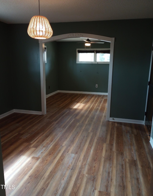 spare room with wood finished floors, a ceiling fan, and baseboards