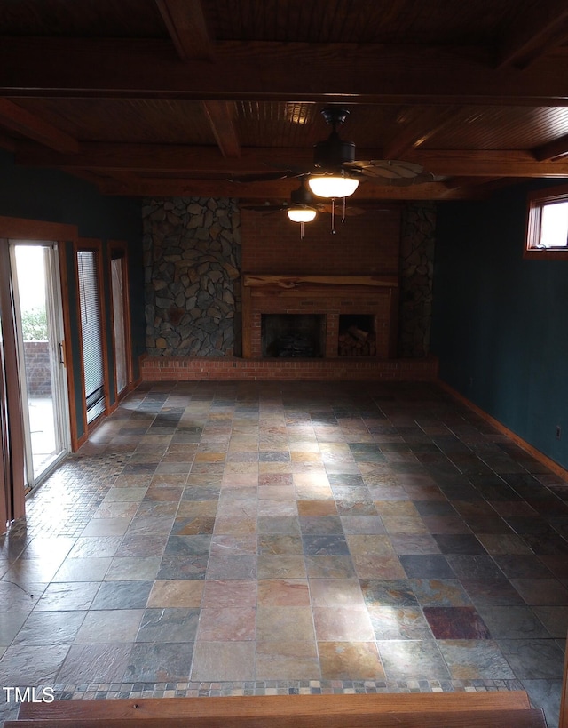 unfurnished living room featuring wood ceiling, a fireplace, beam ceiling, and ceiling fan