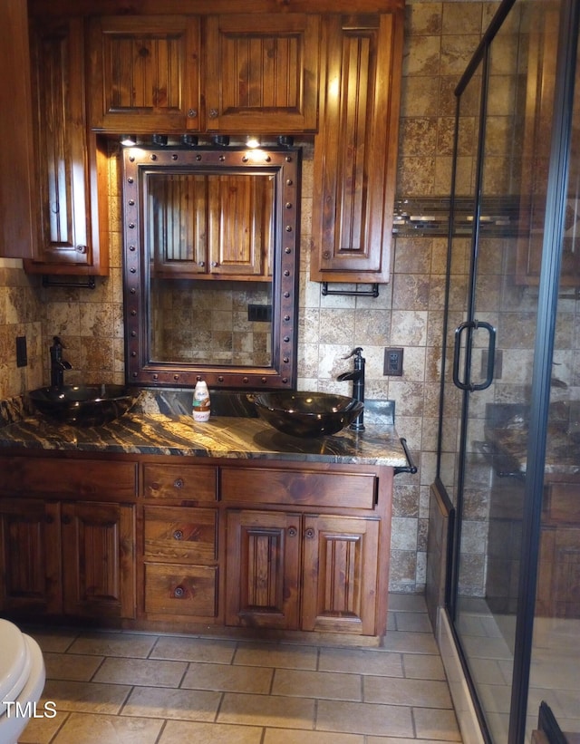 kitchen with tasteful backsplash, stone counters, and a sink