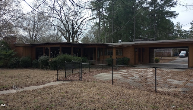 rear view of property featuring a fenced front yard, a chimney, and an attached carport