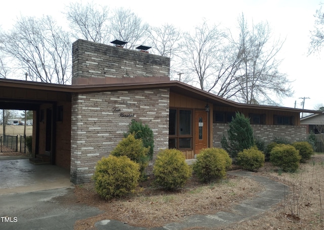 view of side of home featuring driveway, an attached carport, and brick siding