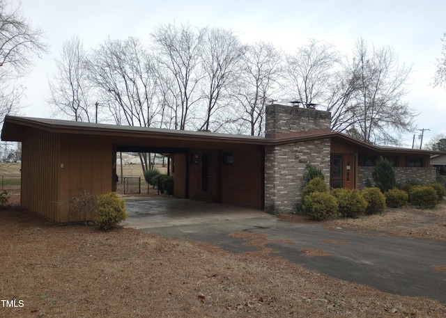 view of side of property featuring brick siding, a chimney, and an attached carport