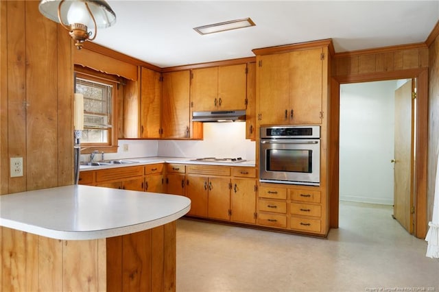 kitchen featuring oven, white gas cooktop, a sink, light countertops, and brown cabinets