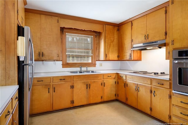 kitchen with under cabinet range hood, a sink, light countertops, appliances with stainless steel finishes, and brown cabinetry