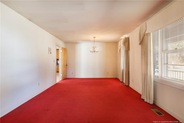 carpeted empty room with visible vents, a notable chandelier, and baseboards