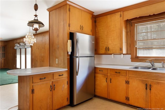 kitchen with light countertops, brown cabinetry, a sink, and freestanding refrigerator