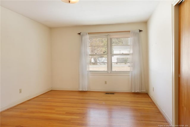 unfurnished room featuring baseboards, visible vents, and light wood finished floors