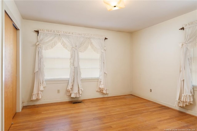 empty room with visible vents, baseboards, and wood finished floors