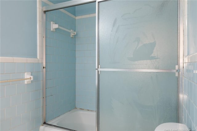 bathroom featuring toilet, enclosed tub / shower combo, and tile walls