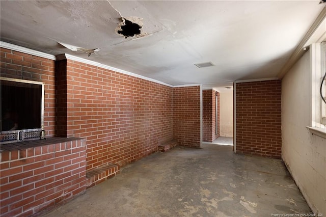 empty room featuring concrete flooring, brick wall, ornamental molding, and visible vents