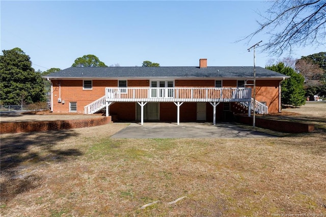 rear view of property featuring brick siding, a yard, a deck, and stairs