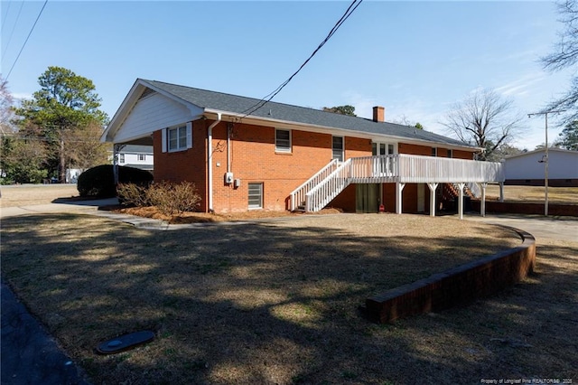 rear view of property with brick siding, a lawn, a chimney, and stairs