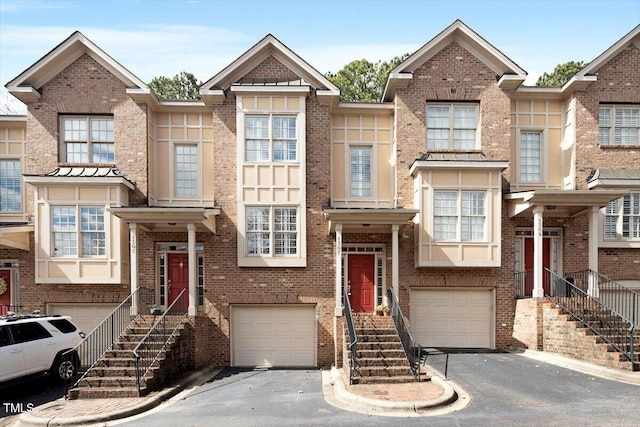 multi unit property featuring a garage, aphalt driveway, and brick siding