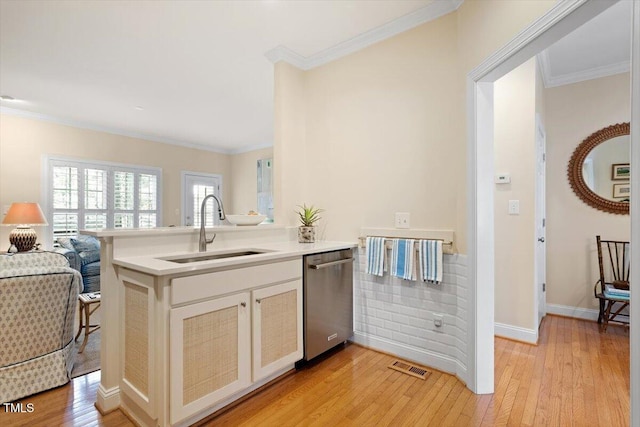 kitchen with a sink, light wood finished floors, visible vents, and dishwasher