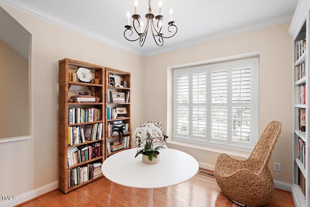 living area with baseboards, visible vents, wood finished floors, crown molding, and a notable chandelier