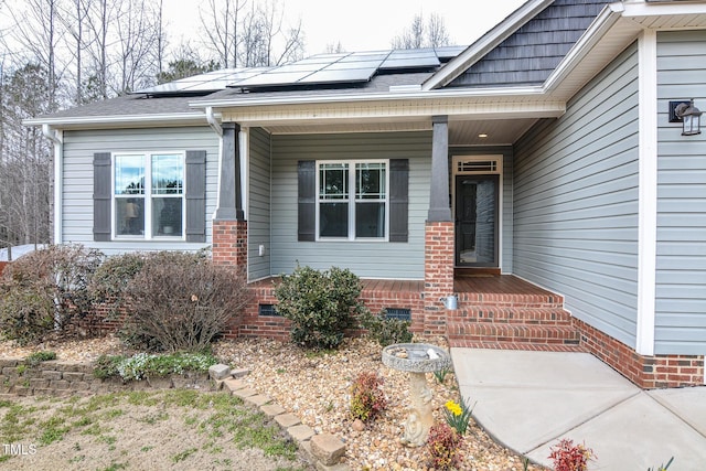 doorway to property featuring a porch, crawl space, a shingled roof, and roof mounted solar panels