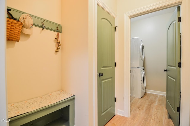 mudroom featuring baseboards, stacked washer and clothes dryer, and light wood-style floors