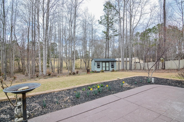 view of yard featuring fence, a patio, and an outdoor structure