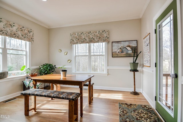 dining area featuring light wood-style flooring, visible vents, ornamental molding, and baseboards