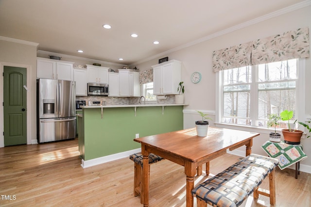 dining room with recessed lighting, crown molding, and light wood finished floors