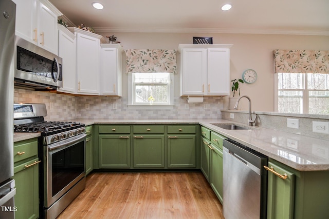 kitchen featuring stainless steel appliances, a sink, white cabinetry, and green cabinetry