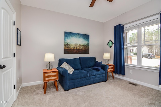 carpeted living room featuring a ceiling fan, visible vents, and baseboards