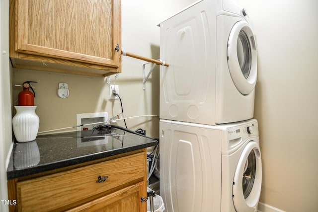 laundry area with stacked washer / drying machine and cabinet space