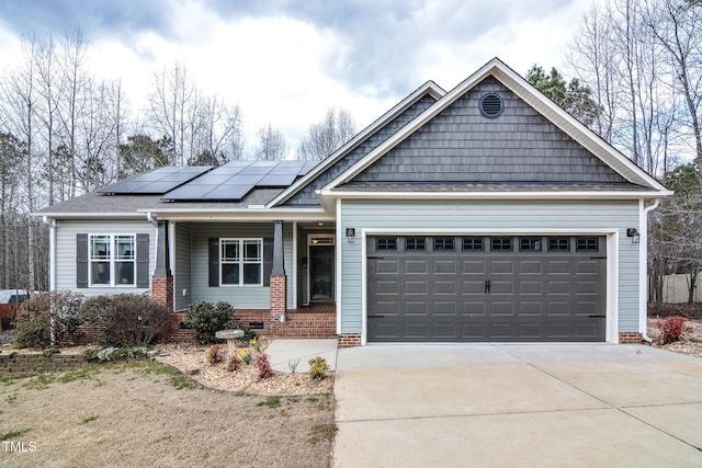 craftsman-style house with a shingled roof, solar panels, concrete driveway, an attached garage, and a porch