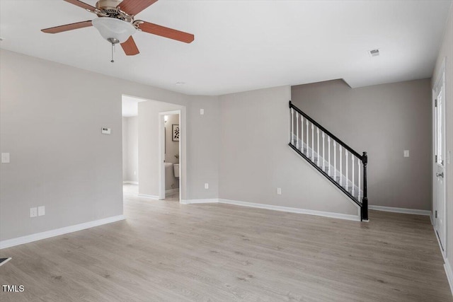 unfurnished living room featuring visible vents, baseboards, stairs, light wood-style flooring, and a ceiling fan