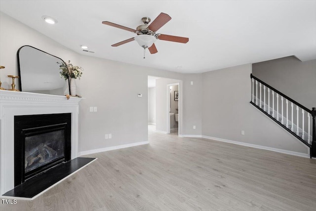 unfurnished living room with stairway, wood finished floors, baseboards, visible vents, and ceiling fan