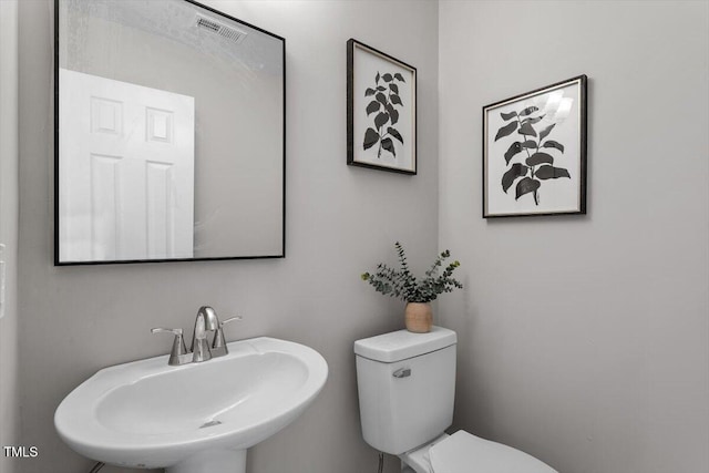 half bath featuring a sink, visible vents, and toilet