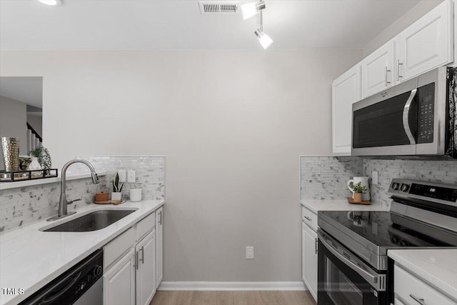 kitchen with a sink, stainless steel appliances, light countertops, white cabinetry, and tasteful backsplash