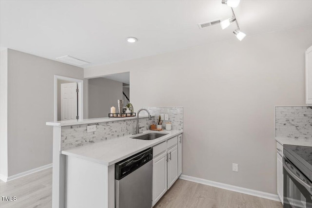 kitchen with visible vents, a peninsula, a sink, appliances with stainless steel finishes, and backsplash