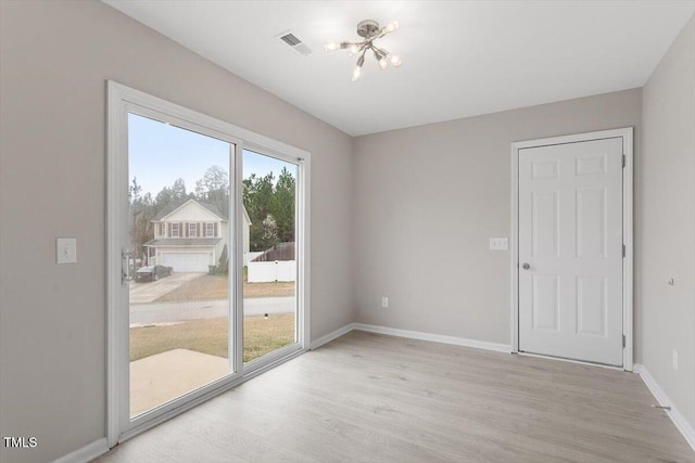 unfurnished room with light wood-style flooring, baseboards, visible vents, and a chandelier