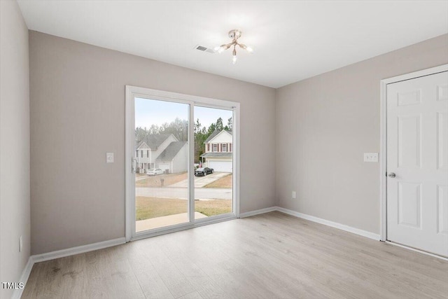 spare room featuring wood finished floors, visible vents, and baseboards