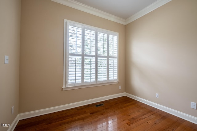 spare room featuring ornamental molding, hardwood / wood-style floors, visible vents, and baseboards