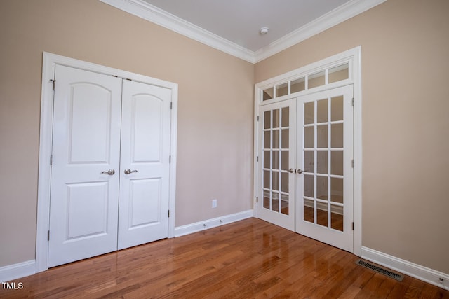 unfurnished bedroom with wood finished floors, visible vents, baseboards, french doors, and crown molding