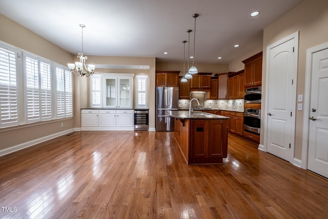 kitchen with appliances with stainless steel finishes, beverage cooler, brown cabinetry, and dark wood finished floors