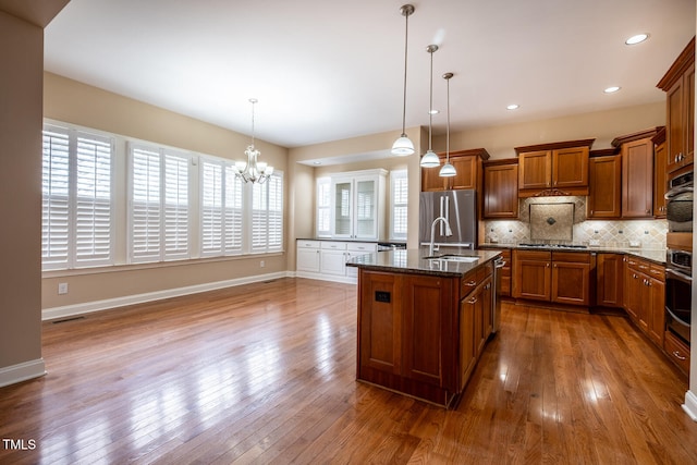 kitchen with decorative backsplash, dark wood-style floors, brown cabinets, stainless steel appliances, and a sink