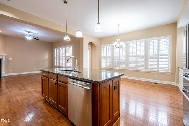 kitchen featuring stainless steel dishwasher, brown cabinetry, a sink, and light wood-style floors