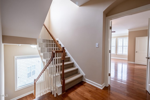 staircase featuring ornamental molding, wood finished floors, and baseboards