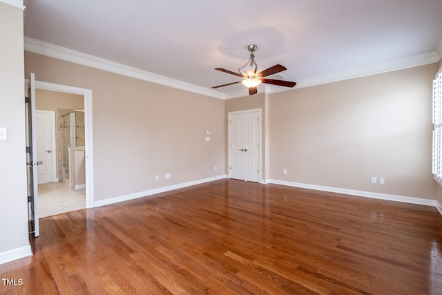 unfurnished room with ornamental molding, wood finished floors, and baseboards