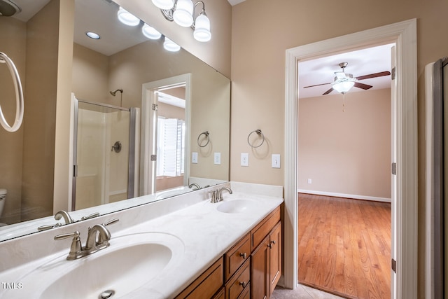 full bath featuring double vanity, a shower stall, ceiling fan, and a sink