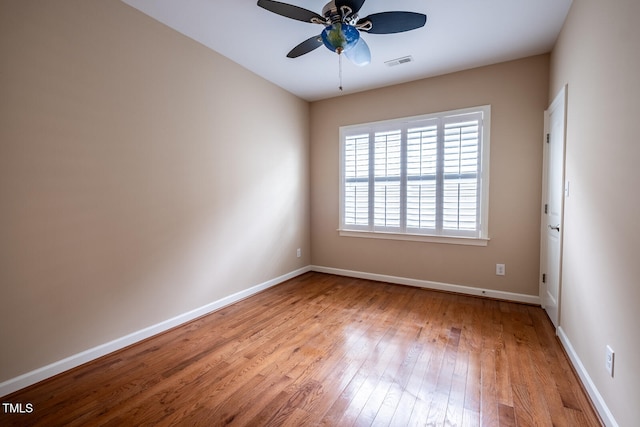 unfurnished room featuring baseboards, visible vents, ceiling fan, and hardwood / wood-style floors