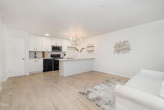 kitchen with light countertops, white cabinets, light wood-type flooring, a peninsula, and black appliances